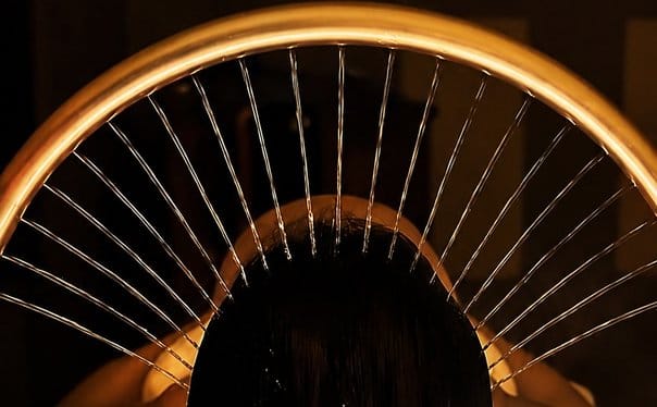 Fanned metal massage rods held above a client's head during a scalp treatment