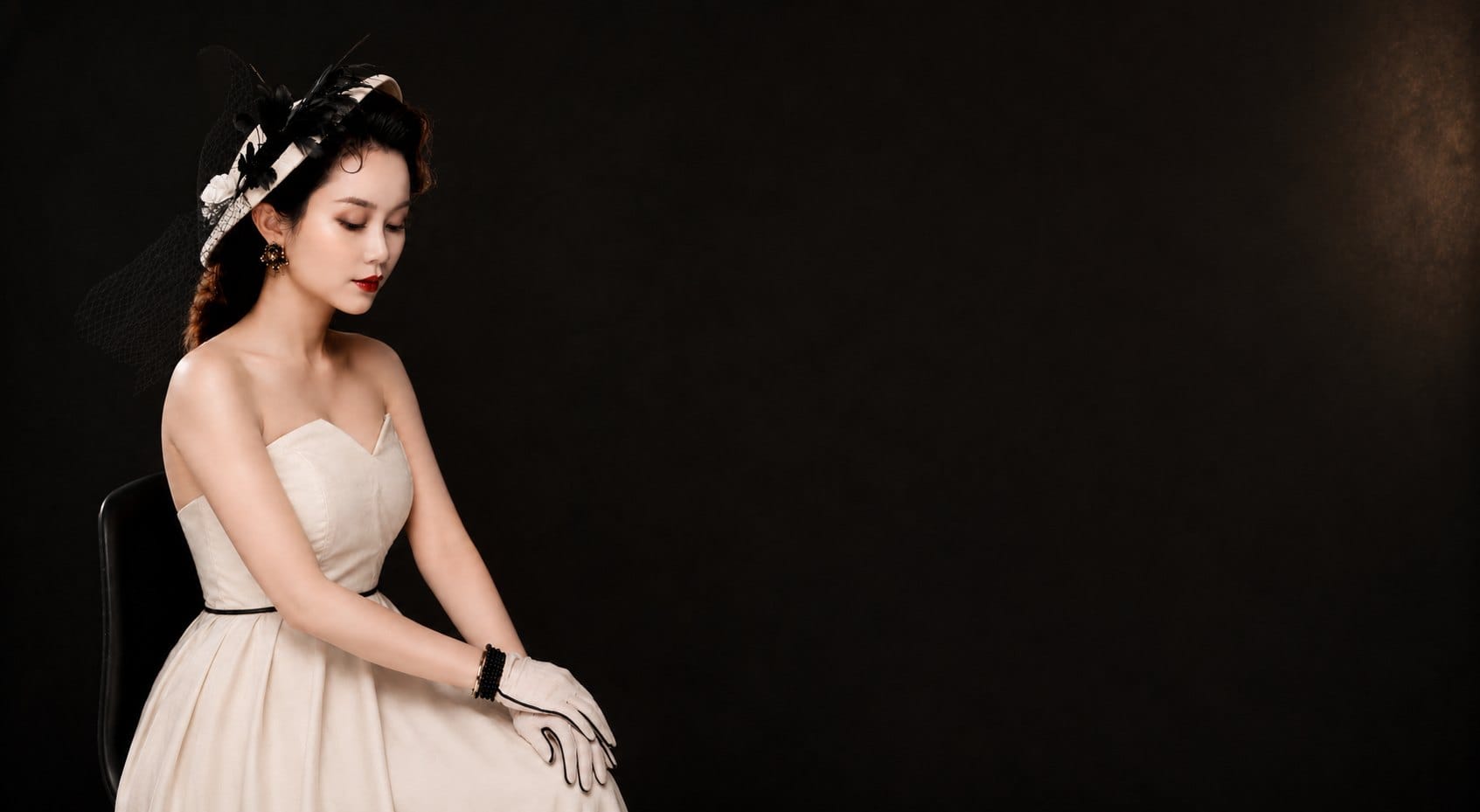 Son, founder and lead artist of Sonthuy Beauty, seated in an ivory gown in the Tucson studio